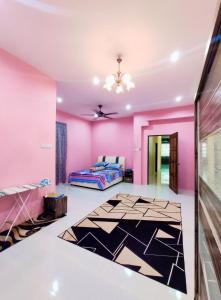 a pink bedroom with a bed and a black and white rug at Villa Mikayla Homestay - Alor Setar in Alor Setar