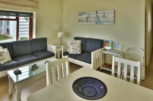 a living room with couches and a table and chairs at Sea Cottage in Langebaan