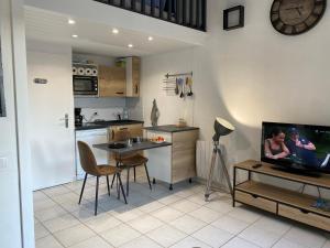 uma cozinha com uma mesa e uma televisão numa cozinha em Villa Domaine des Pins, Magasins proches, Piscine em Fréjus