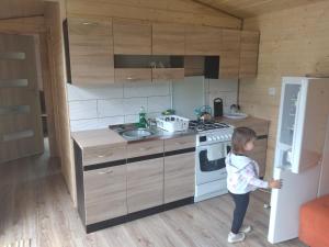 a little girl standing in a kitchen with a stove at Agroturystyka u Wioli i Irka , domek u Ireny, spływy kajakowe in Karsin