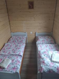 two beds in a room with wooden walls at Agroturystyka u Wioli i Irka , domek u Ireny, spływy kajakowe in Karsin
