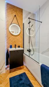 a bathroom with a shower and a sink with a mirror at Apartment Przyfabryczny Księży Młyn - Garaż - Klimatyzacja - FV in Łódź