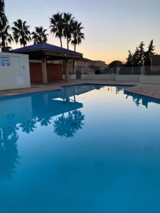 een zwembad met blauw water voor een gebouw bij Villa Domaine des Pins, Magasins proches, Piscine in Fréjus