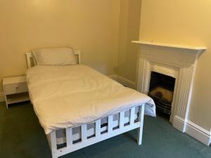 a bed in a room with a fireplace at Rooms In A Victorian Comfortable 4-bedroom house in Milton Keynes Rooms Not En-suites in Wolverton