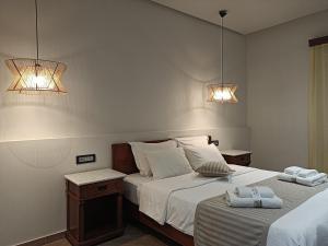 two beds in a bedroom with two lights on the wall at The Flower Of Monemvasia Hotel in Monemvasia