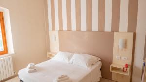 a bedroom with a bed with a striped wall at Hotel La Smorfia in Castiglioncello
