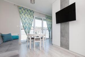 a living room with a dining room table and a tv at DreamHouse Apartament „PIASKOWY” ul. Północna 18 C, Darłówko Wschodnie in Darłówko