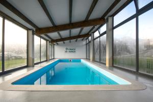 a swimming pool in a house with large windows at Hotel Rural O Cruce do Burgo in Friol