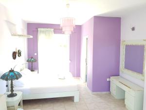 a bedroom with a white bed and purple walls at STELLAS HOUSE POLYCHRONO in Polykhrono