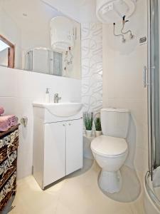 a white bathroom with a toilet and a sink at Apartament Kameralny na Starówce in Gdańsk