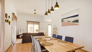 een eetkamer en een woonkamer met een houten tafel en stoelen bij Villa Jarcia by Calima Villas in Caleta De Fuste