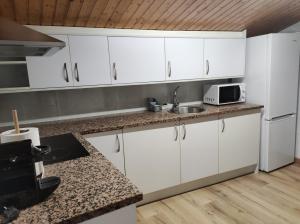 uma cozinha com armários brancos e um lavatório em APT 3 Àtic acollidor al Centre de Vic - APTGARBI em Vic