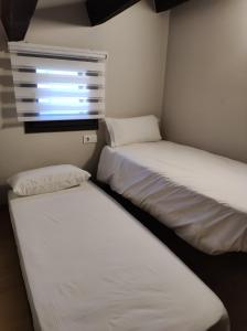 two beds in a small room with a window at APT 3 Àtic acollidor al Centre de Vic - APTGARBI in Vic