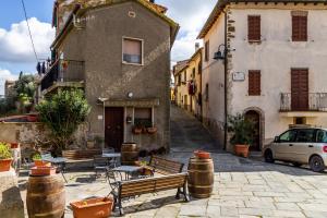 una strada con due edifici e un'auto e barili di Casa Pereta a Magliano in Toscana