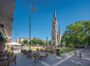 a street with tables and chairs and a clock tower at Sunny rooms at Danube in Budapest