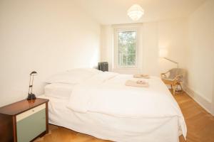 a bedroom with a large white bed and a window at Spacious apartment next to park with free BaselCard in Basel