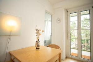 Una habitación con una mesa con un jarrón de flores. en Spacious apartment next to park with free BaselCard, en Basilea
