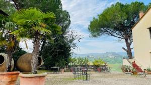 un giardino con tavoli, sedie e un albero di Corte Di Valle a Greve in Chianti