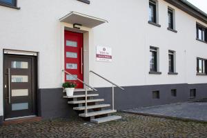 a white building with a red door and stairs at Meinel's Inn in Dreifelden