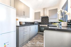 een keuken met witte kasten en zwarte aanrechtbladen bij Severn Street House Serviced Accommodation in Leigh