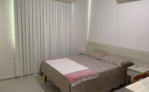 um quarto com uma cama e uma janela com persianas em Residencial Lúcia Silvestre em Florianópolis