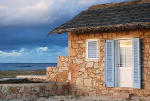 a stone building with a window and the ocean at Spinguera Ecolodge in Espingueira