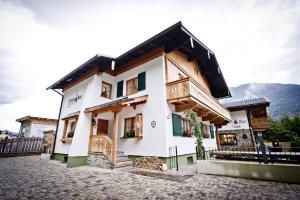 a white building with a balcony on a street at Chalet & Apartments Tiroler Bua in Achenkirch