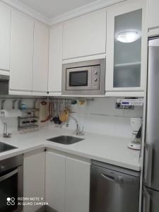 a white kitchen with a sink and a microwave at Bermejo Apartamento in Candás +12 photos