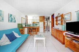 a living room with a blue couch and a kitchen at Bungamerica272 in Playa de las Americas