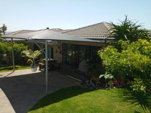 a patio with an umbrella on a house at Bee Comfy in Klein Brak Rivier