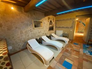 a room with four white chairs and a stone wall at I SEI FILARI in Capannori