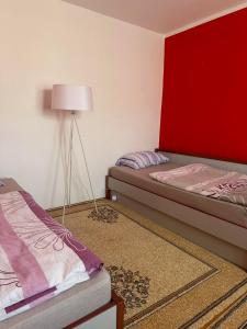 1 dormitorio con 2 camas y pared roja en Apartman Zaga, en Trebinje