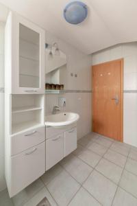 ein weißes Badezimmer mit einem Waschbecken und einem Spiegel in der Unterkunft Apartma Metka in Medvode