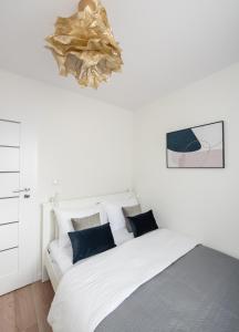 a white bedroom with a white bed with blue pillows at Chmielna Marble City Centre Apartment in Warsaw