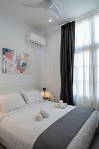 a white bedroom with a large bed and a window at Central Suites Aegina 1 in Egina