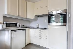 cocina blanca con armarios blancos y microondas en Bright 2 bedroom flat with terrace in Notting Hill, en Londres