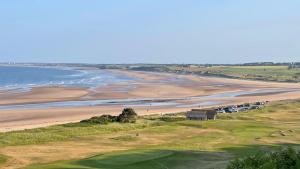 a view of a golf course and the beach at St Bede Beach Hut in Alnmouth