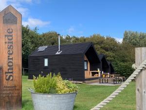 a black cabin with a sign in front of it at St Bede Beach Hut in Alnmouth