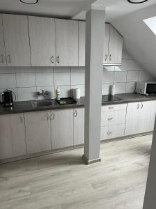an empty kitchen with white cabinets and a pole at Pokoje na Górce in Rajgród