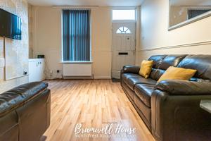 a living room with a leather couch and wooden floors at St Helens Contractor Accommodation in Saint Helens