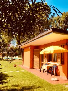 een geel huis met een tafel en een paraplu bij Casa Adriana in Costermano