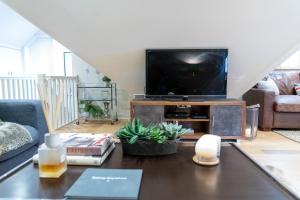 ein Wohnzimmer mit einem TV und einem Tisch in der Unterkunft Hertford Barn conversion in Hertford