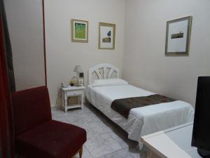 a hotel room with two beds and a chair at Hotel Tanausu in Santa Cruz de Tenerife