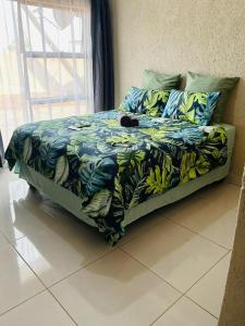 a bed with a blue and green blanket with bananas on it at 2NIGHTS GUEST HOUSE in Mokopane