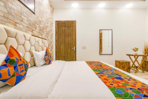 1 dormitorio con cama y pared de ladrillo en FabHotel Sky Lark Farm en Ludhiana