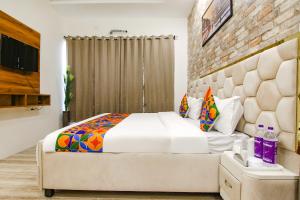 1 dormitorio con 1 cama grande y pared de ladrillo en FabHotel Sky Lark Farm en Ludhiana