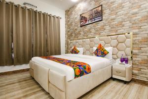 Un dormitorio con una cama grande y una pared de ladrillo. en FabHotel Sky Lark Farm, en Ludhiana