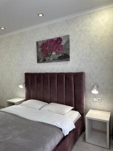 ein Schlafzimmer mit einem großen Bett mit einem lila Baum in der Unterkunft Новая современная квартира в центре города in Qostanai