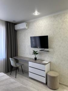 Schlafzimmer mit einem Schreibtisch und einem TV an der Wand in der Unterkunft Новая современная квартира в центре города in Qostanai