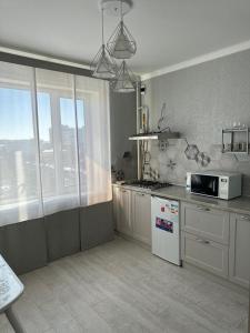 eine Küche mit einer Mikrowelle und einem Kühlschrank in der Unterkunft Новая современная квартира в центре города in Qostanai